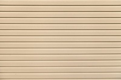 Light brown (beige) vinyl wooden siding panel background with imitation wood texture.