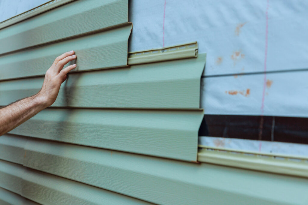 Contractor installing vinyl siding panels